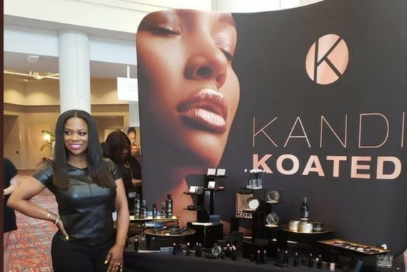 Kandi Coated Makeup: Bedroom Kandi, image of Kandi Burruss in front of a banner and display for her new cosmetics.