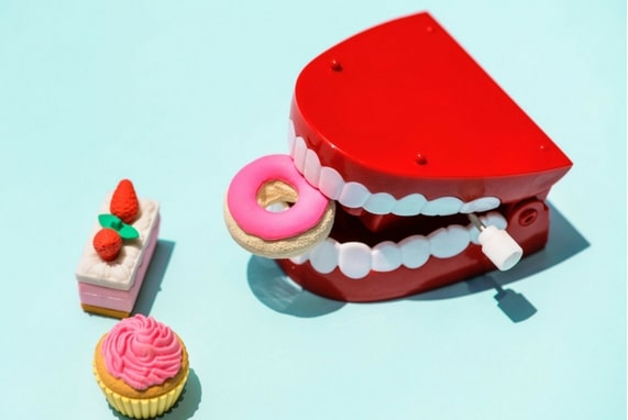 Summer 100. Oral Play Is Not A Game, image of a wind up toy teeth and toy pastries.