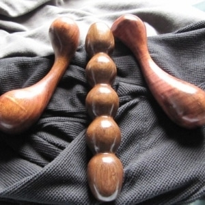 Lumberjill, adult wooden sex toys, image of grey and white fabric under three different shaped, handcrafted, wooden dildos.