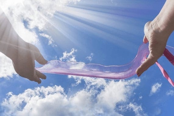Backwoods Bedroom, blue clear sky, woman's hands holding a pink waterslyde adult toy.